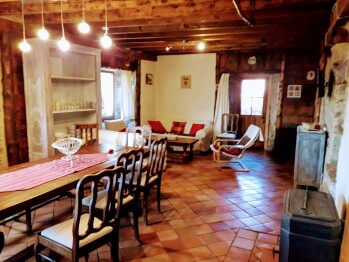 The living room of the Ker Carlines holiday home, its large wooden table for meals, and the log stove.