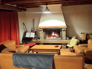 The lounge area of the Ancolie holiday home, its leather armchairs, and the massive fireplace.